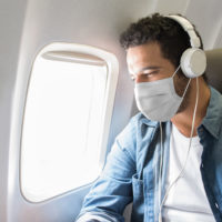 A man wearing his mask on a plane.