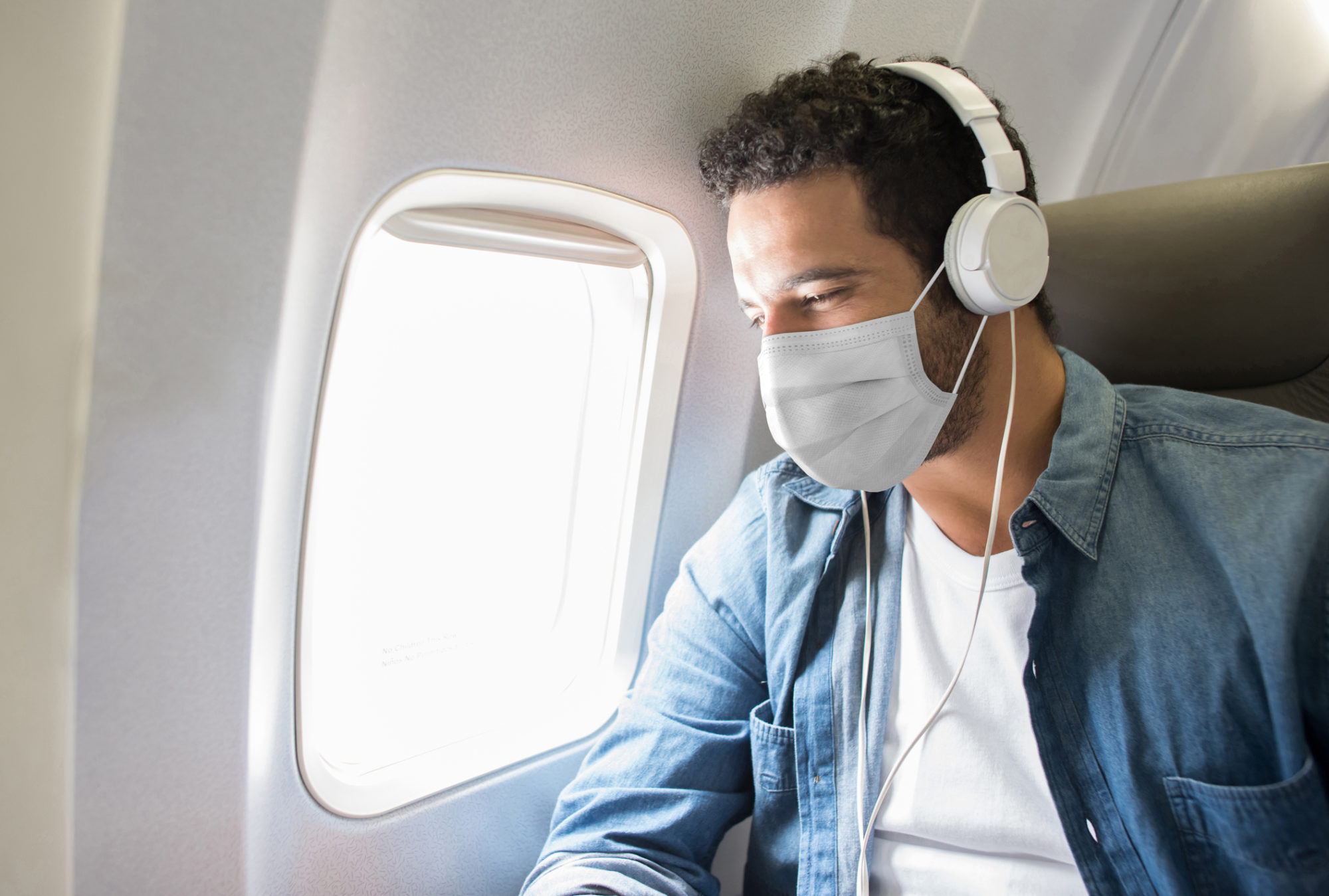 A man wearing his mask on a plane.