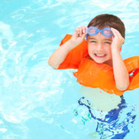 A child swimming with goggles and floaties.