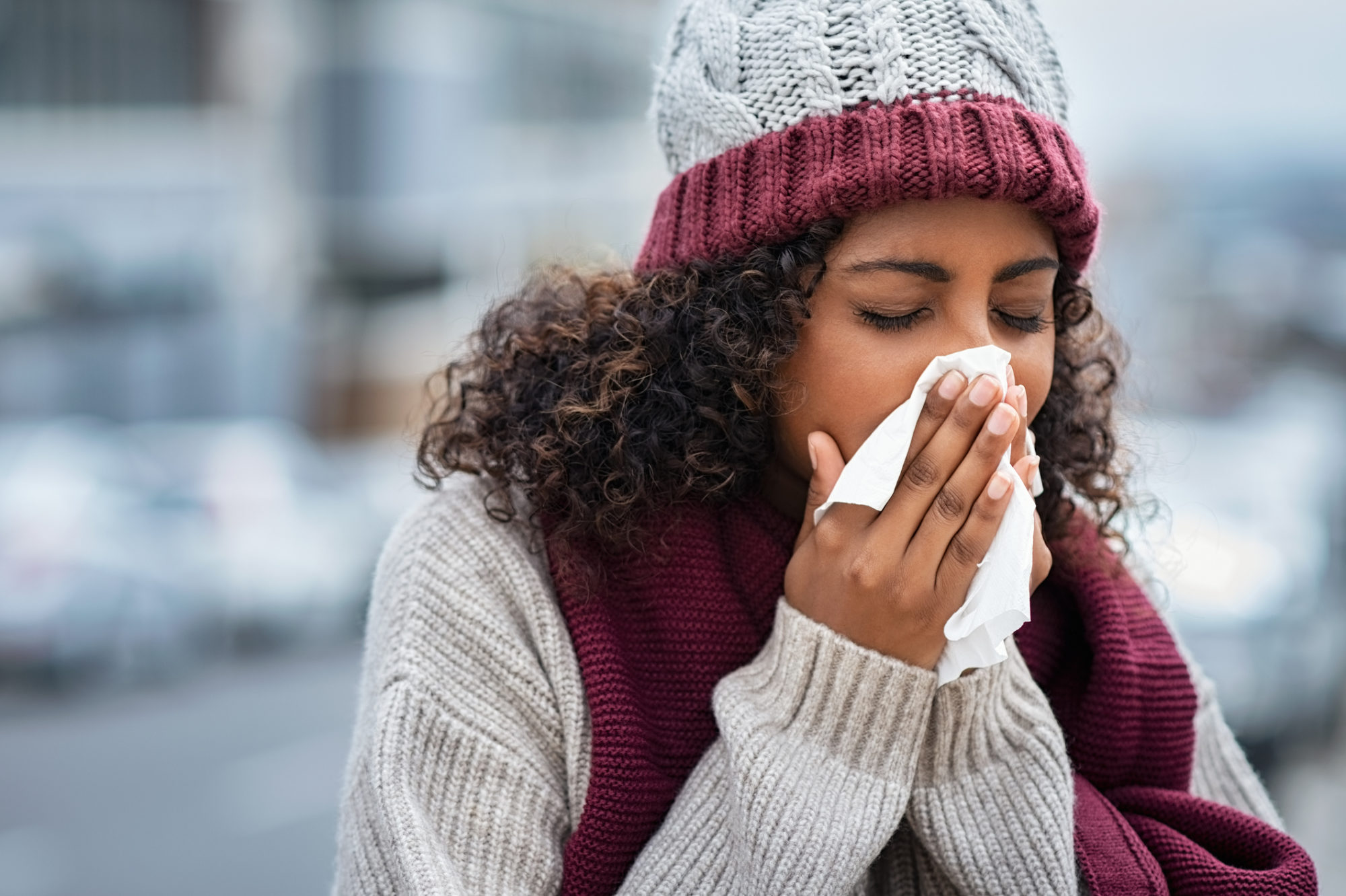 A woman blowing her nose in the cold.