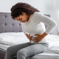 African American woman holding painful stomach due to a UTI