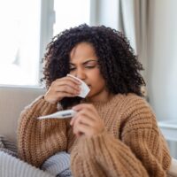 African American woman reading a thermometer to check her temperature.