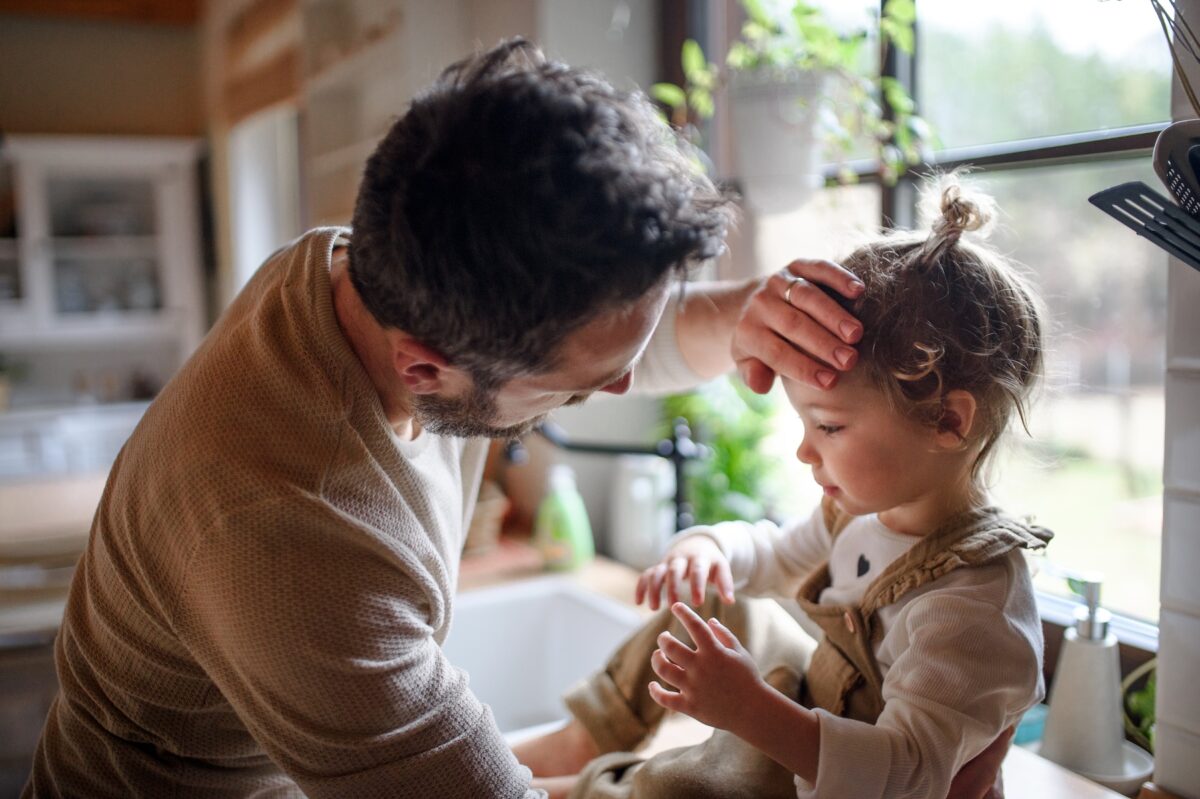 Father checking yong daughter's forehead for fever