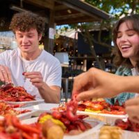 Young man and woman laughing while eating crawfish