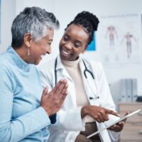 Smiling African American doctor and elderly patients reviewing results on tablet