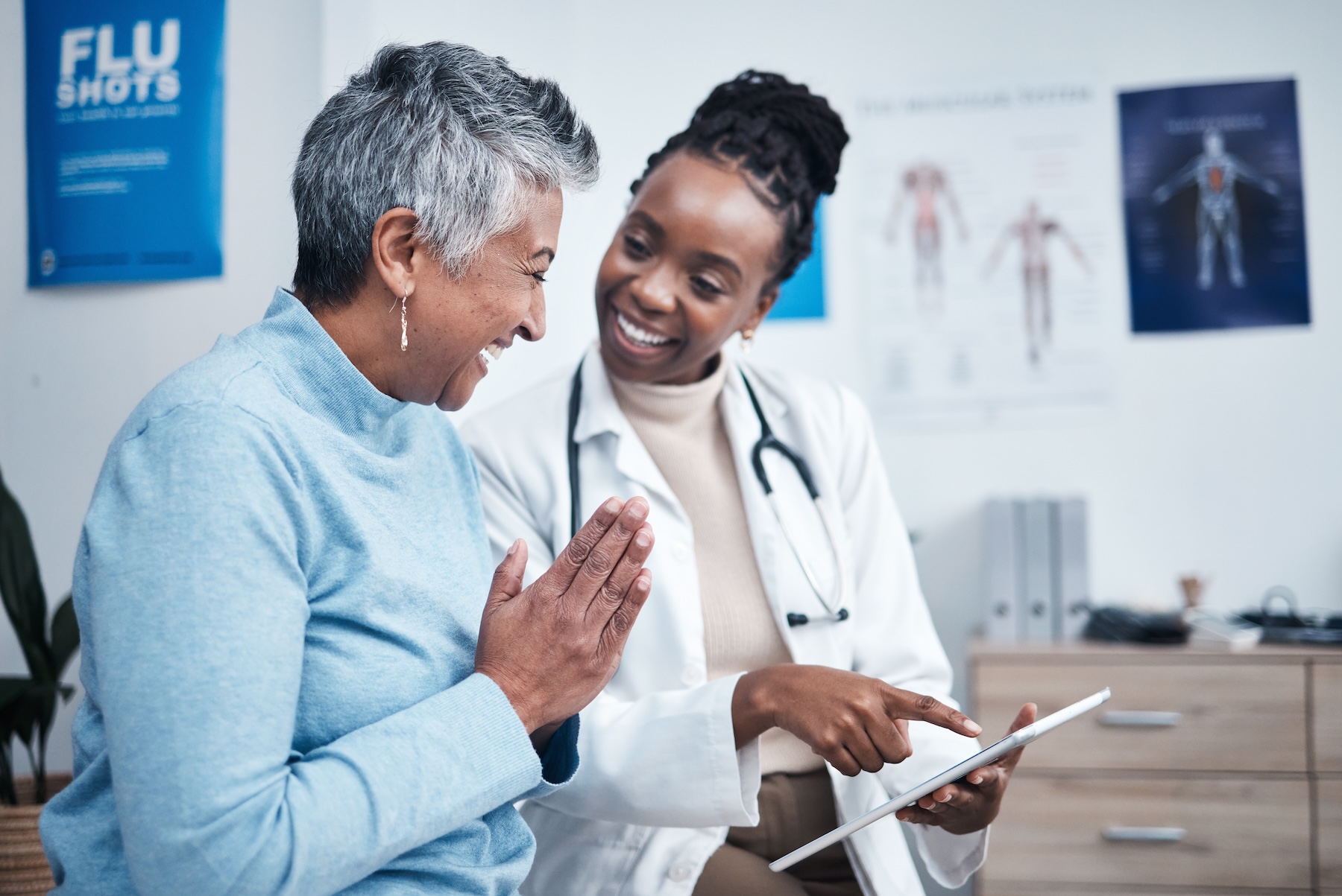Smiling African American doctor and elderly patients reviewing results on tablet
